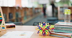 Empty desk, education and learning with books, toys and expandable ball to play in kindergarten. Table, back to school and textbook in classroom with paper flower for creative art or math with abacus