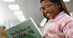Education, child and student in library reading book for information, learning or knowledge on dinosaurs. Scholarship, smile and Indian girl with textbook for growth, development or project research