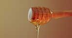 Honey, drip and stick in studio for nutrition, antioxidants and natural sugar. Raw, organic sweetener and drizzling on brown background for healthy food, antibacterial properties and gut health