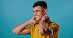 Frustrated man, neck injury and pain with ache in stress, muscle tension or strain in studio on a blue background. Young male person or model with sore spine, bruise or inflammation from fibromyalgia