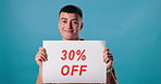 Poster, sale and face of man on blue background for 30 percent promotion, information and sign. Happy, advertising and portrait of person with banner for retail discount, deal and bargain in studio