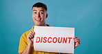 Poster, discount and face of excited man on blue background for promotion, information and sign. Happy, advertising and portrait of person with banner for retail sale, deal and bargain in studio