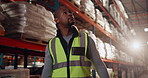 Logistics, black man and walking in warehouse with boxes, storage management and shipping export. Delivery, transport and inspection worker in plant for distribution, supply chain or stock inventory