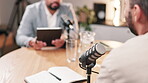 Interview, microphone and tablet with influencer men in recording studio for live radio broadcast. Media, news or podcast with talk show host and guest streaming subscription service content on air