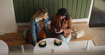 Phone, friends and girls talking in coffee shop for hangout, reunion and meeting together above. Mobile, people and relax in cafe for conversation, gossip and story on social media app on womens day