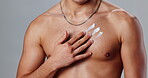 Skincare, hand and cream on chest in studio for routine, healthy skin and moisturizing. Man, body and topless on gray background with lotion, sunscreen protection and dermatology product application