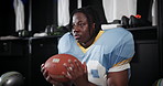 Black man, football and player thinking with ball in locker room for match, game or half time. Young African or athlete getting ready or preparation in wonder for sports tournament or competition