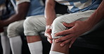 Knee, injury and hands with player in locker room, muscle tension and football with sports. Closeup, people or guy with health risk, game or hurt with training, holding leg or athlete with joint pain