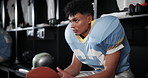 Black man, football and serious player thinking with ball in locker room for match, game plan or half time. Young African or athlete getting ready or preparation for sports tournament or competition