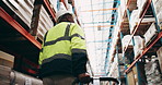 Businessman, back view and warehouse with trolley for transportation service, supply chain or packing inventory. Man, contractor or employee moving stock with loader for logistics on shelves at depot