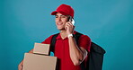 Man, boxes and courier with phone call in studio for talking, delivery or package distribution address. Cargo, supply chain or driver in conversation with customer, transportation and blue background