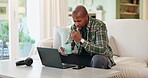 Black man, home and thinking on laptop with coffee on sofa for research on house finance or loan application. Male person, couch and living room on website with comparing for mortgage interest rate 