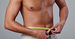 Man, lingerie and measuring tape on waist for results, fitness and weight loss with healthy diet in gray background. Male person, pride and wellness for exercise, progress and confidence with stomach