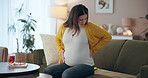 Home, back pain and pregnant woman on sofa, ache and inflammation in living room. Maternity, apartment and girl on couch, spine injury or physical strain with body ache, tummy and pregnancy in lounge