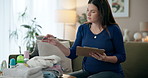 Pregnant, woman and home with clipboard for baby clothes or equipment and checklist on shopping. Female person, mother and maternity on sofa in living room with gifts or present for unborn child. 