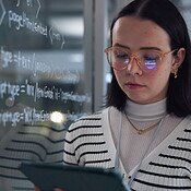 Woman, tablet and coding for solution in office with equation on glass ...