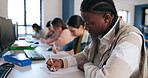 Desk, writing and black student in classroom for learning, lecture or lesson at university. Computer, notebook and scholarship with learner or pupil in school class for assessment, report and study