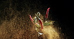 Spice, ingredients and chicken with chili in explosion for flavour, food or powder in studio on a black background. Closeup of seasoning, crumbs or natural organic products with peppers for cuisine