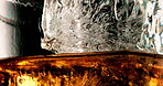 Glass, ice and pour liquid in studio for enjoyment, closeup and cold beverage. Frozen cube, tumbler and whiskey flow on black background with liquor, brandy and aesthetic for testing in distillery