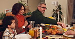 Food, happy family and serving dinner in home for thanksgiving celebration at night. Child, mom and dad share meal, corn or eating healthy vegetables in plate with interracial people bonding together