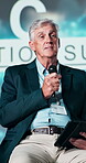 Conference, speaker and businessman with microphone on stage for economy development, event and speech. Government, summit and mature panelist with tablet for future, innovation and global policy