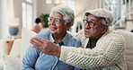 Home, sofa and elderly couple pointing in conversation for retirement, connection and discussion. Weekend, communication and senior people in love with support, information and explaining direction