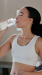 Fitness, woman and drinking water in home for yoga, hydration and healthy body. Female person, peace and bottle of liquid for wellness, detox and aid for digestion in living room for pilates session