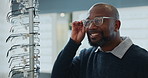 Man, optometry and choosing spectacles for eye care, medical professional and consultation at optometrist. Male person, glasses and decision in clinic or ophthalmology center for size, frame and lens