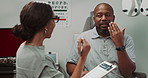 Optometrist, document and patient for eye exam of healthcare report, vision assessment and medical history. Doctor, man and discussion with clipboard, sight information and appointment notes in office