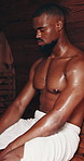 Black man, sauna and relax with towel for hot steam, sweat or stress relief at indoor salon. Young African or muscular male person in heat room for relaxation, detox or muscle and health treatment 