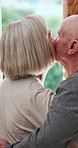 Elderly couple, back or cheek with kiss or hug in love, care or support together at retirement home. Senior man and woman in embrace, intimacy or romance by door window for morning affection at house