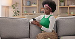 Home, typing and black woman on sofa, smartphone and social media with message, internet and relax. African person, apartment and girl with cellphone, texting and online chatting with mobile user