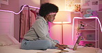 Laptop, black woman and student typing in bedroom, reading book and study with neon light. Education, night and girl elearning on computer for knowledge or research for college entrance test in home