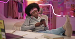 Girl, phone and texting at night in home, books and study with break for game, chat or reading post. Black woman, smartphone and relax in bedroom with neon light, mobile app or social media in house