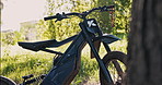 Ebike, grass field and tree with nature for extreme sport, off road race or countryside terrain. Closeup, electric bike or stationery vehcile with handles, suspension or wheels for cycling in dirt