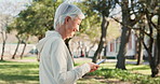 Phone, walking and senior woman in nature for exercise, activity and read online news. Smile, outdoor and elderly female person with workout for cardiac health in park, garden or field on cellphone.