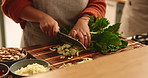 Hands, kitchen and woman chop spinach for cooking healthy dinner, meal or culinary food at home. Knife, ingredients and closeup of female person cut vegetables for diet, nutrition or wellness supper.