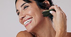 Gua sha, happy and woman in studio with natural, health and lymphatic drainage treatment. Skincare, face and female person with jade tool for facial wrinkles or blood circulation by white background.