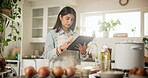 Food, recipe and tablet with woman in kitchen of home for cooking ingredients or instructions on internet.  Apron, preparation and search with Indian person in apartment for diet, health or nutrition