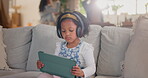 Girl, child and tablet for sound in home, watching video and headphones for listening to podcast. Female person, kid and playing games in living room to ignore parents fighting, song and streaming