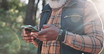 Hiking, smartphone and man with nature, hands and typing for direction, digital app and hobby. African person, traveller and hiker with cellphone, social media and internet with trees and mobile user