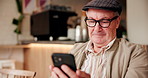 Coffee shop, relax and senior man with phone for internet, online games and chat in cafe. Retirement, happy and elderly person on smartphone in restaurant, cafeteria and diner waiting for service