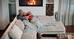 Love, hug and senior couple on sofa for bonding, relationship and commitment by fire. Home, marriage and happy man and woman with blanket on couch for romance, care and relax together in living room