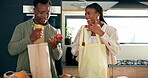 Black couple, happy and unpacking in kitchen with groceries, food stock or fresh fruit for health. Man, woman or smile in home with apples, love and produce in shopping bag with support or chat