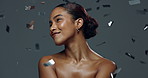 Smile, skincare and beauty of woman with confetti isolated on gray studio background. Makeup, cosmetics and happy model with glitter for glow, creative aesthetic and laughing at new year celebration