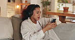 Headphones, cellphone and woman on sofa in home listening to music, podcast or playlist for blog review. Relax, phone and female freelance critic with audio tech for streaming new album at apartment.