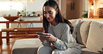 Woman, phone and happy with texting on sofa, reading and notification with mobile app in living room. Person, smile and smartphone on couch for chat, contact and relax with scroll on social network