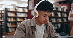 Student, headphones and man on laptop in library typing for education, university and knowledge. College, music and person on technology for studying research for project assignment and assessment