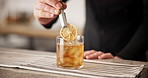 Hands, bartender and lemon in cocktail for drink preparation, beverage and closeup in pub. Alcohol, glass and barman with fruit slice on ice to garnish old fashioned whiskey on rocks for decor or art