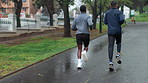 Men, running and back with exercise in nature for cardio, wellness and support in fitness training. Runner, friends and athlete with challenge at park for sports, endurance and workout in morning